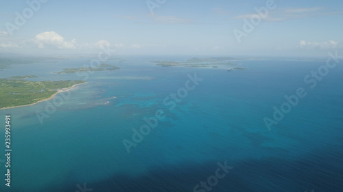 Aerial view of Groups islands with sand beach and turquoise water in blue lagoon among coral reefs, Caramoan Islands, Philippines.
