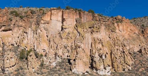 Panorama of highly textured, colorful high cliffs, caves, and ancient native American ruins an cliff dwellings in Bandelier National Monument near Santa Fe, New Mexico