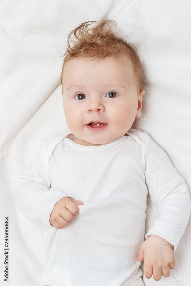 Happy child on the white blanket, top view Happy child on the white blanket, top view