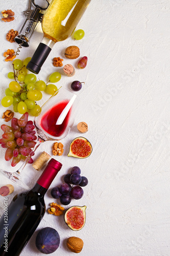 Glass and bottle of wine with fruits and nuts on white background. Wine still life with copy space. top view, vertical