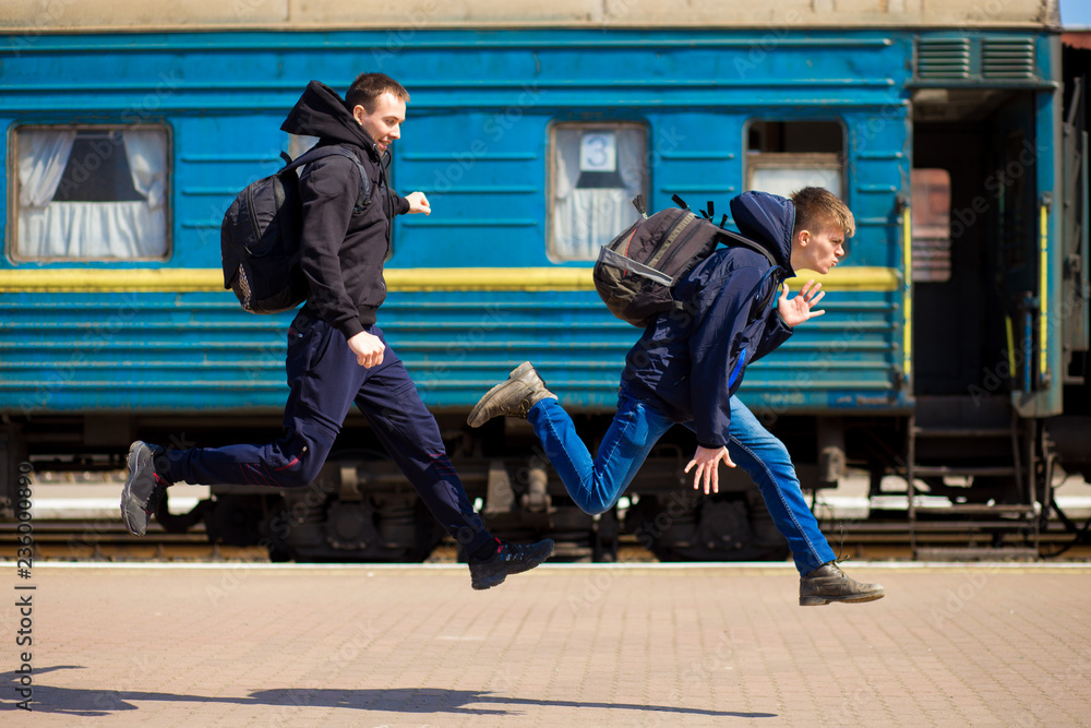 Obraz premium Two man with big bags run at railway station. Travel by train