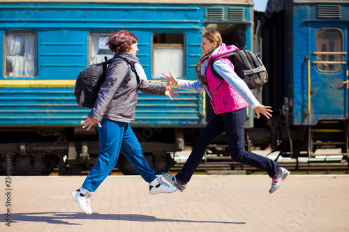 Two woman with backpack run at railway station. Travel concept