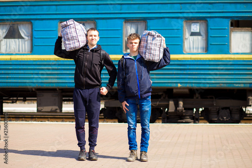 Foto Two man with big bags at railway station. Travel by train