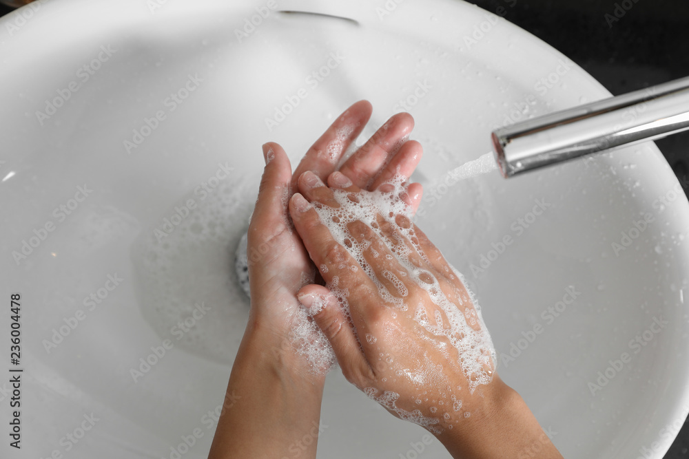 Fototapeta premium Woman washing hands with soap over sink in bathroom, top view
