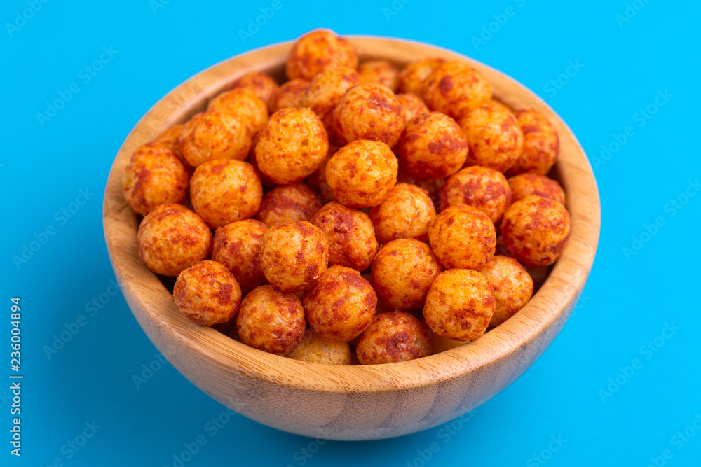 Bacon puff balls in wooden bowl on bright colorful background Bacon puff balls in wooden bowl on bright colorful background