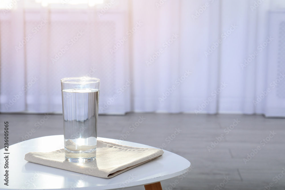 Glass of water on table against blurred background. Space for text Glass of water on table against blurred background. Space for text