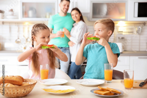 Little children having breakfast with toasts in kitchen