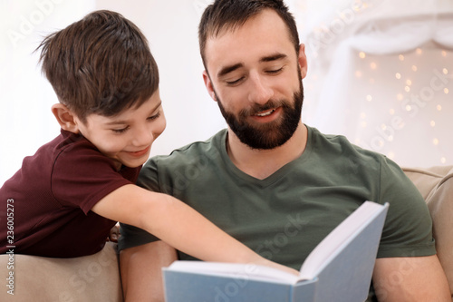 Man reading book to his child at home