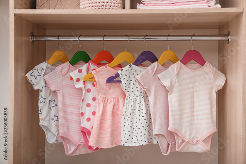 Hangers with baby clothes on rack in wardrobe photo