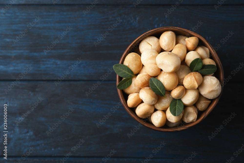 Bowl with shelled organic Macadamia nuts and space for text on blue wooden background, top view Bowl with shelled organic Macadamia nuts and space for text on blue wooden background, top view