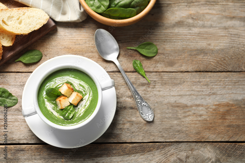 Flat lay composition with fresh vegetable detox soup made of spinach with croutons in dish and space for text on wooden table Flat lay composition with fresh vegetable detox soup made of spinach with croutons in dish and space for text on wooden table