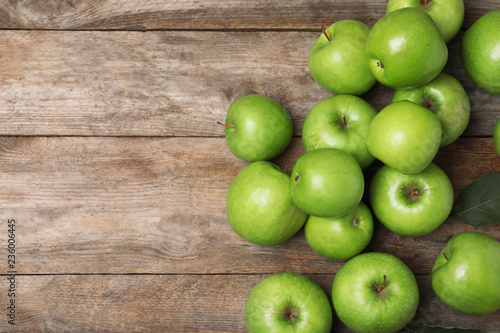 Many juicy green apples and space for text on wooden background, top view