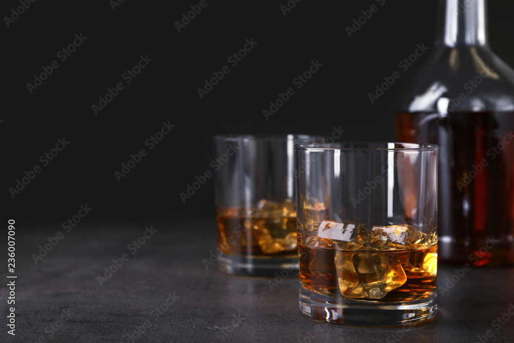 Golden whiskey in glass with ice cubes on table. Space for text Golden whiskey in glass with ice cubes on table. Space for text
