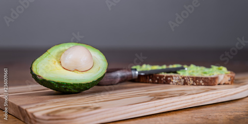 Fresh Organic avocado on a nice, elegant, wooden cutting board on a rustic wooden table with toast and avocado spread