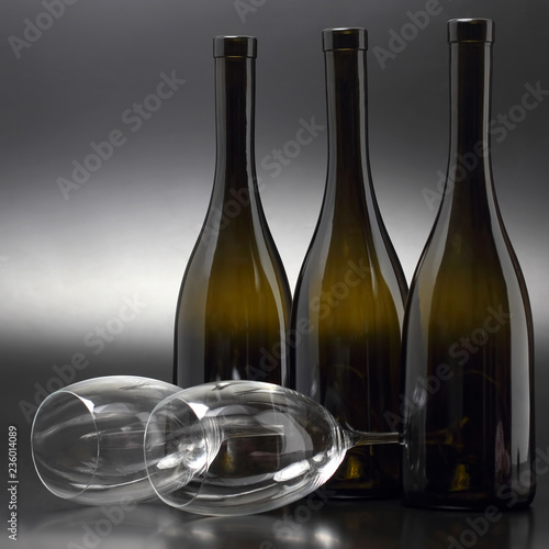 Three wine bottles and two empty wine glasses close up