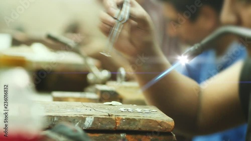 Artisans using tools to fabricate silver jewelry in a workshop. Crafstman welds silver jewelry piece 