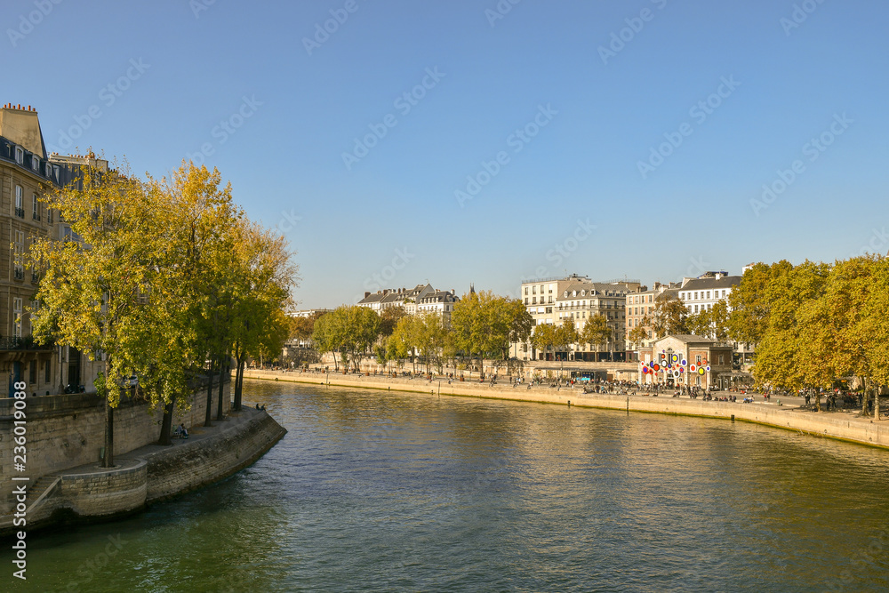 View from the Pont of Sully of the banks of the Seine River with people and autumn trees
