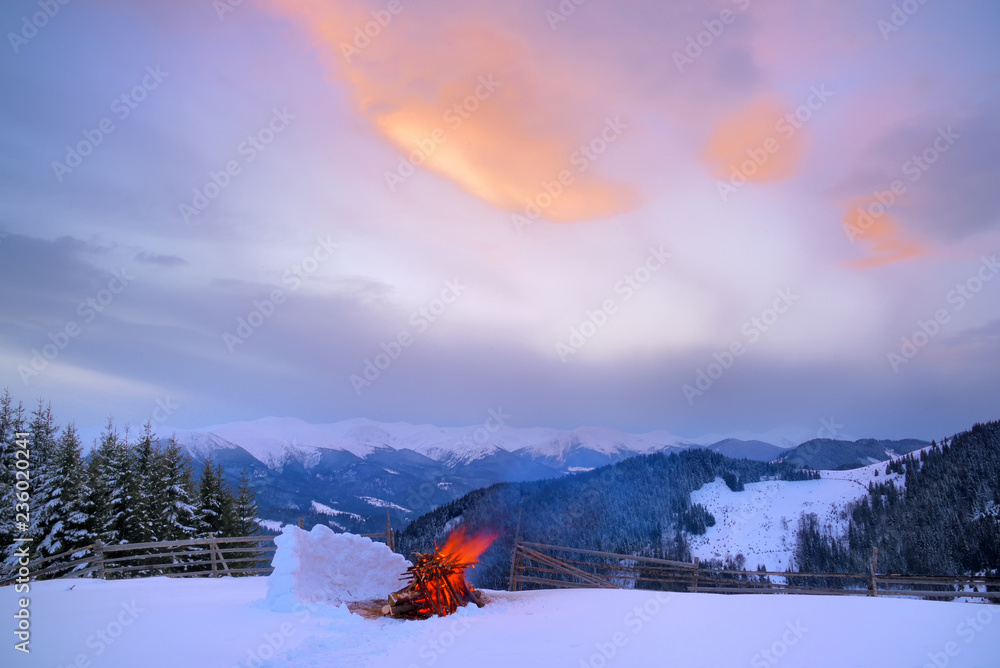 Φωτογραφία A large bright bonfire in the snow and a protective snowy wall from the wind at night in the winter mountains of the Carpathians
