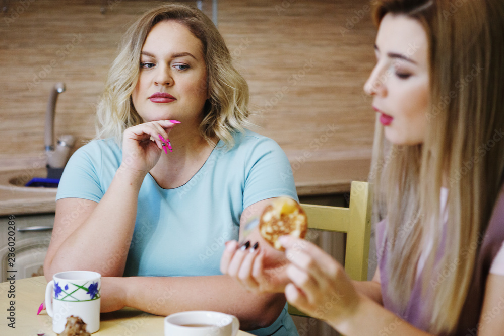Two girlfriends women in the kitchen are having fun and eating food. Two girlfriends women in the kitchen are having fun and eating food.