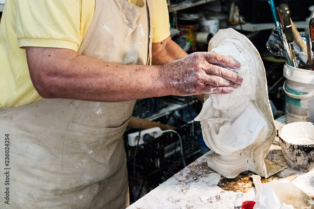 Male hands using plaster to make a bust.