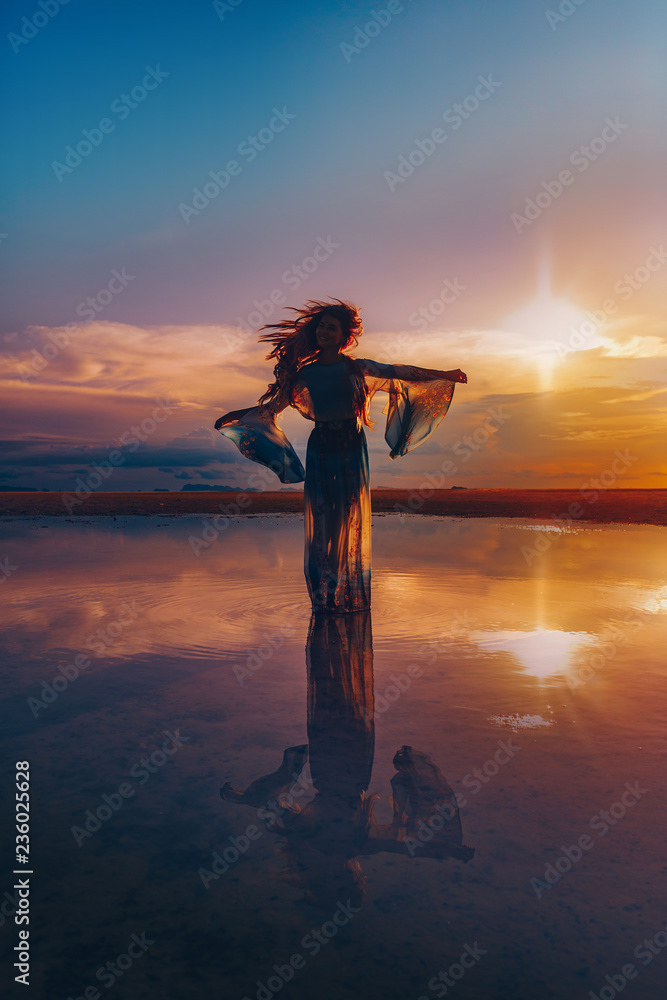 Elegant woman dancing on water. Sunset and silhouette
