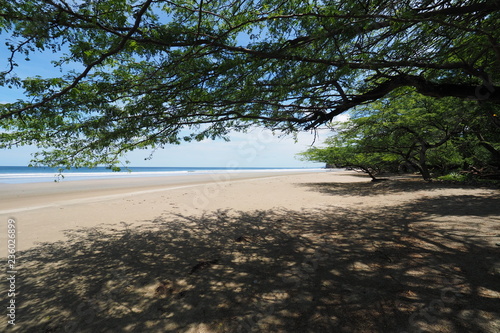 Playa El Coco, Nicaragua, on a sunny summer day showing its beach, rocks, vegetation and cloudscape.