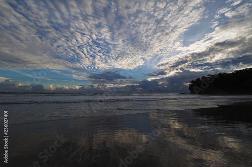Sunset over the beach of Playa El Coco, Nicaragua, with a colorful cloudscape reflected in the coastal water.