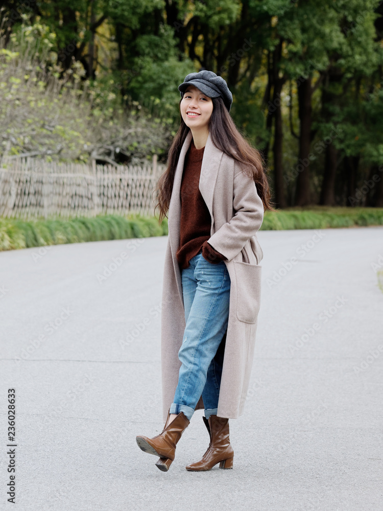 Beautiful young brunette woman in beige coat and blue jean looking and smiling. Outdoor fashion portrait of glamour young Chinese business stylish lady. Emotions, people, beauty and lifestyle concept. Beautiful young brunette woman in beige coat and blue jean looking and smiling. Outdoor fashion portrait of glamour young Chinese business stylish lady. Emotions, people, beauty and lifestyle concept.