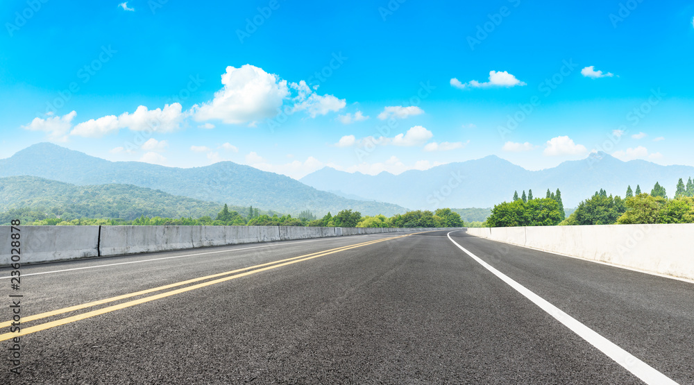 Asphalt road and mountains with white clouds