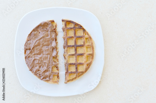 Waffle divided in two halves. Half with hazelnut cream and the half with no topping