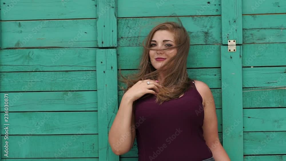 Teen girl with large forms is leaning on a green wooden wall in the summer in the Park, portrait. Slow motion. Plus size model. Teen girl with large forms is leaning on a green wooden wall in the summer in the Park, portrait. Slow motion. Plus size model.