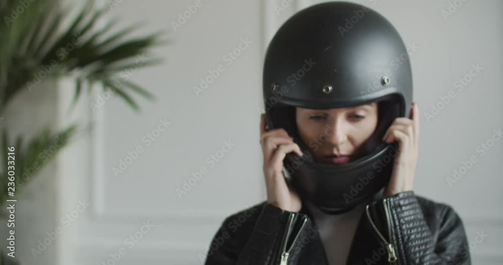 woman putting on retro helmet in bright room woman putting on retro helmet in bright room