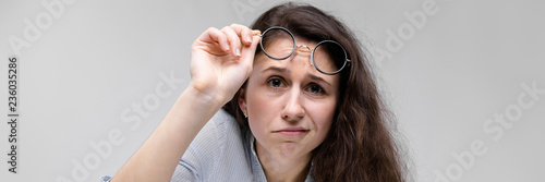 Young brunette girl with glasses. She raised her glasses. photo