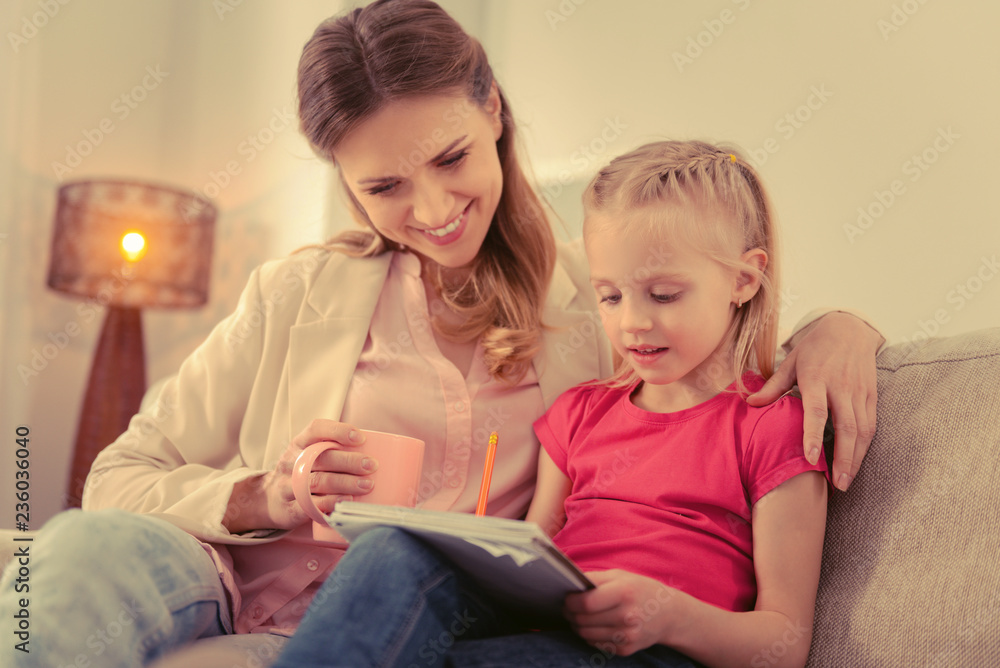 Pleasant cute girl doing her homework with her mother Pleasant cute girl doing her homework with her mother