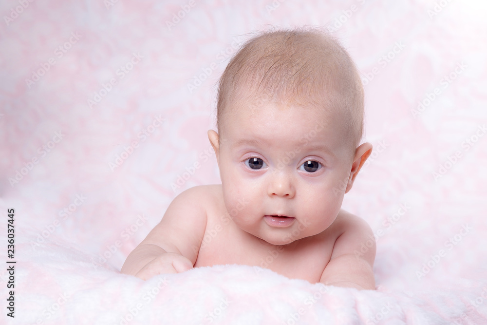 Baby girl in surprise looks on a pink background Baby girl in surprise looks on a pink background