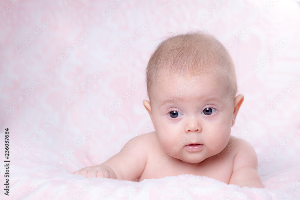 Baby girl in surprise looks on a pink background Baby girl in surprise looks on a pink background