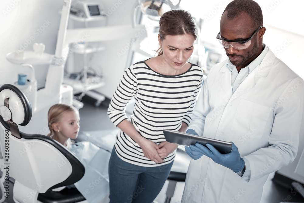 Attentive young woman standing near professional dentist Attentive young woman standing near professional dentist