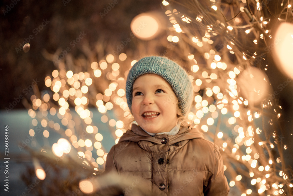 underskud skammel Gør livet portrait of happy girl in winter evenings on background of Christmas lights  Stock Photo | Adobe Stock
