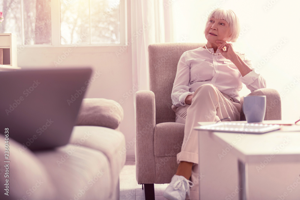 Meditative well-dressed senior lady chilling at home