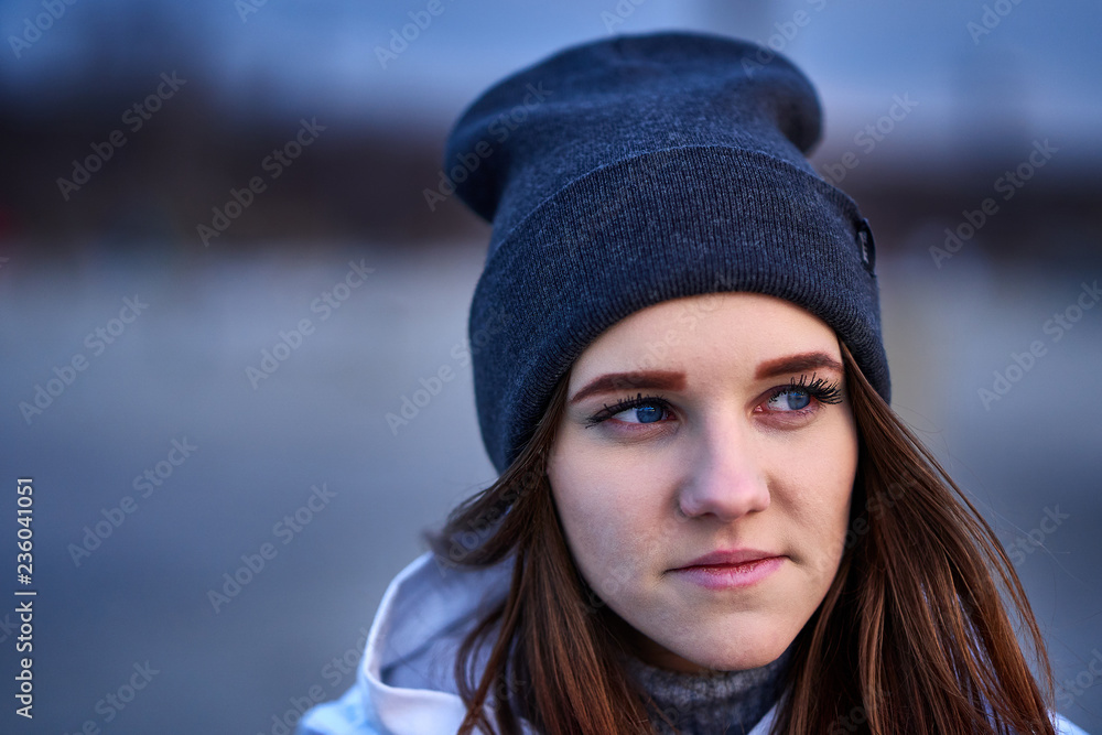 Portrait of a young beautiful girl with dark brown hair in a sports hat in the first rays of the morning rising sun in an autumn cold morning. Portrait of a young beautiful girl with dark brown hair in a sports hat in the first rays of the morning rising sun in an autumn cold morning.