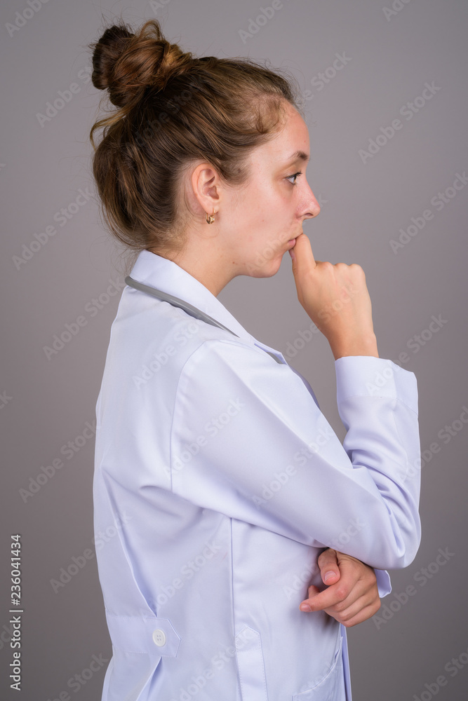 Young beautiful woman doctor against gray background Young beautiful woman doctor against gray background