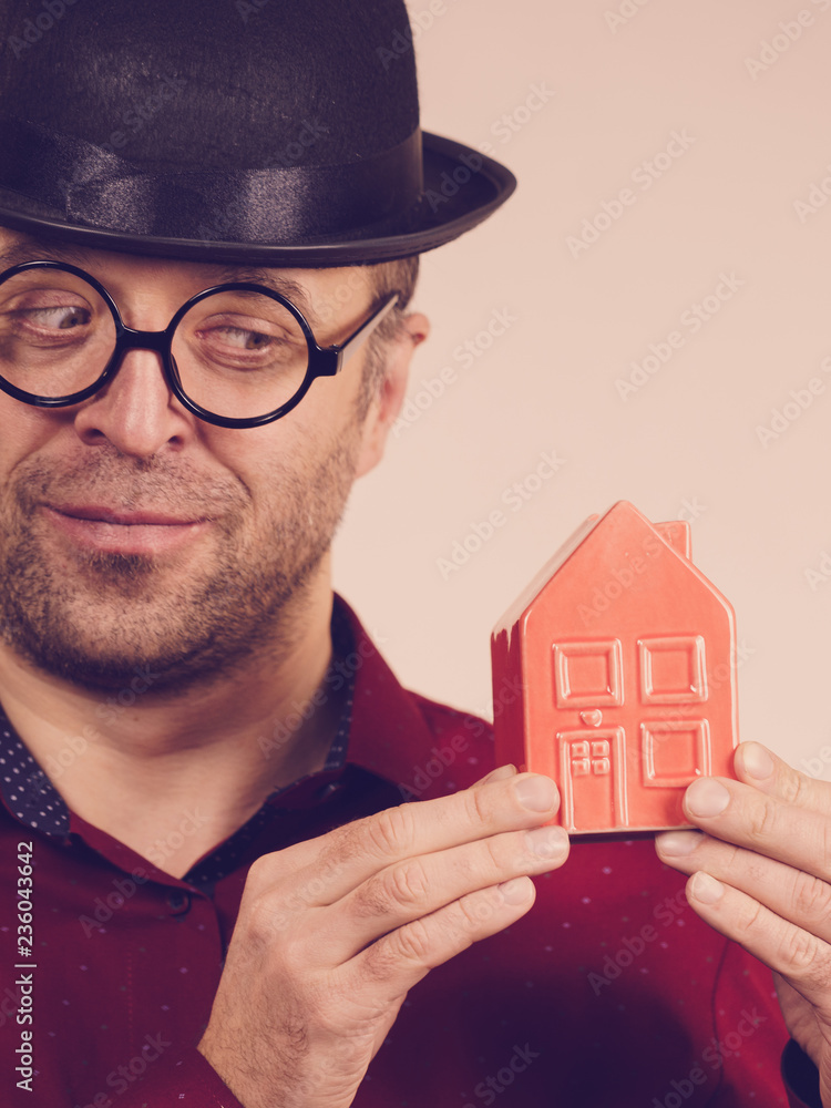 Man wearing funny eyeglasses holding house Man wearing funny eyeglasses holding house