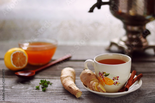 A cup of ginger tea, ginger roots, vintage samovar, lemon and honey