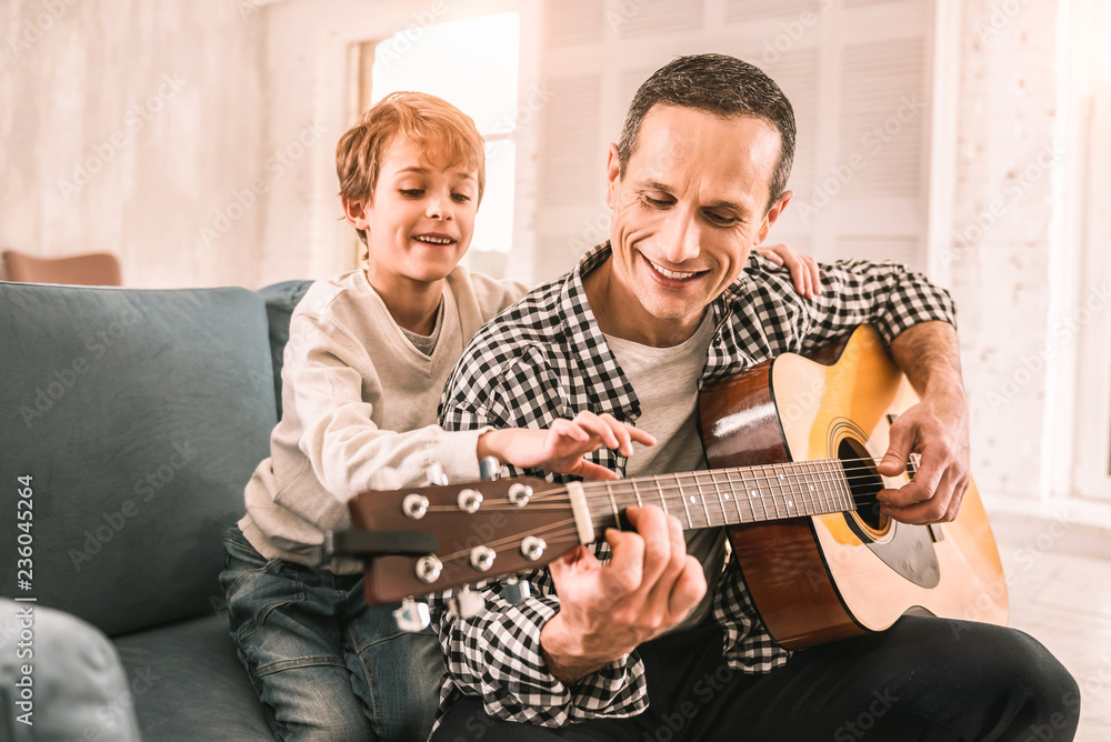 Fototapeta premium Smart little kid giving his dad a piece of musical advice.