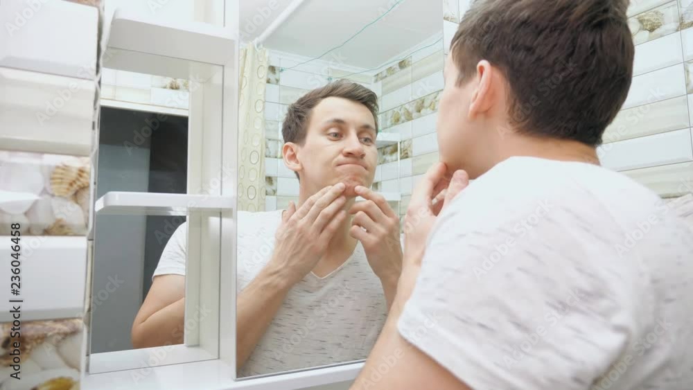 Young man checking his skin in bathroom. Young man checking his skin in bathroom.