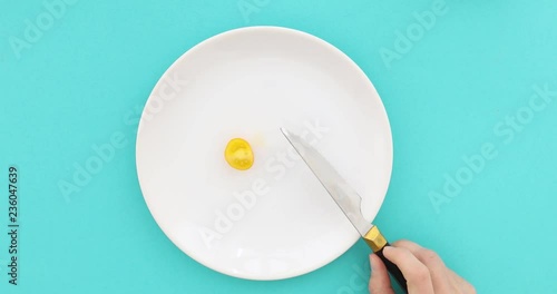 Woman on a diet eats yellow tomato. Female hands with cutlery and empty plate on turquoise background top view, dieting concept photo