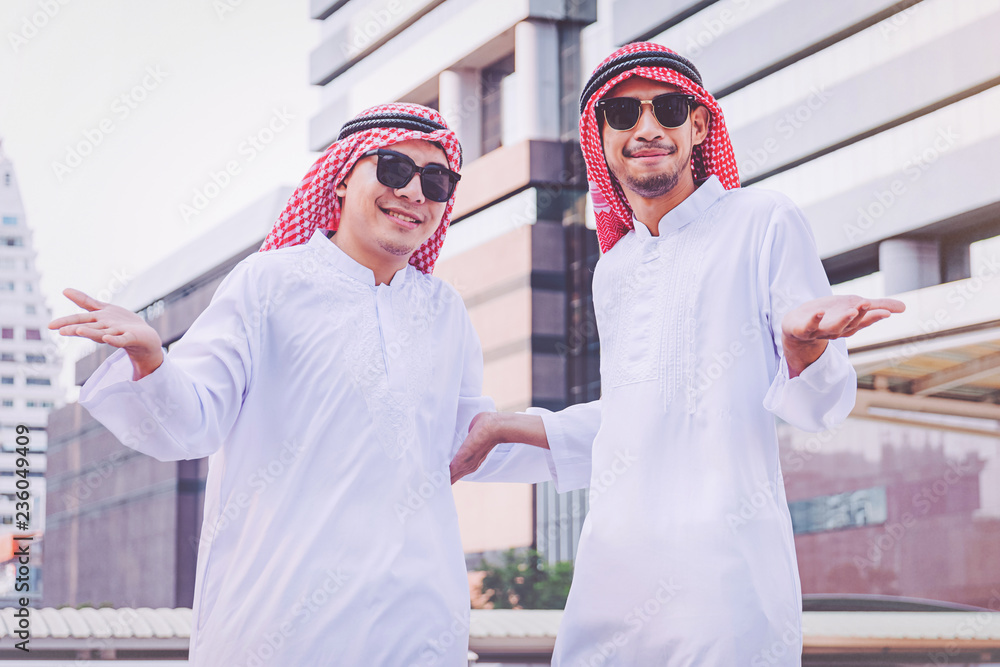 Two Arab businessmen standing by raising both hands up in city Two Arab businessmen standing by raising both hands up in city