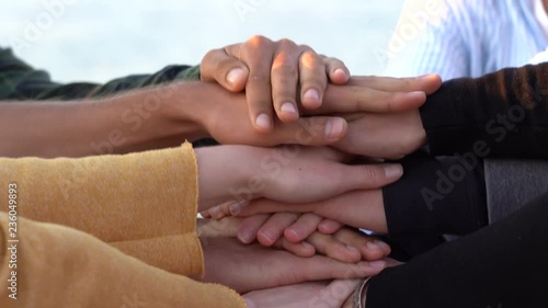 Arm stacked together one by one in unity and teamwork. Many hands getting together in the center of a circle. Close up outdoor shot. Many hands connecting in nature. photo