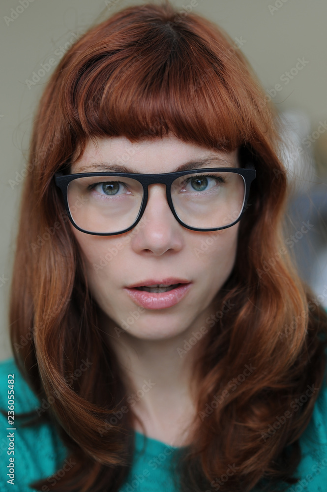 Portrait of a Red Haired Woman with a green Pullover and blue glasses