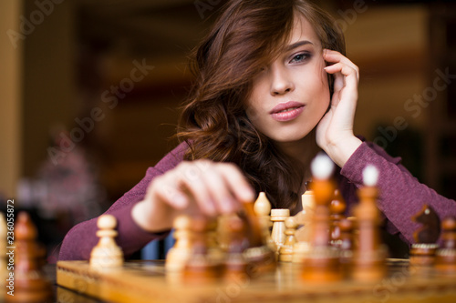 Beautiful brunette woman playing chess. Close up portrait, celective focus.